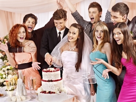 Eine Gruppe von jungen Personen schneiden eine Hochzeitstorte an