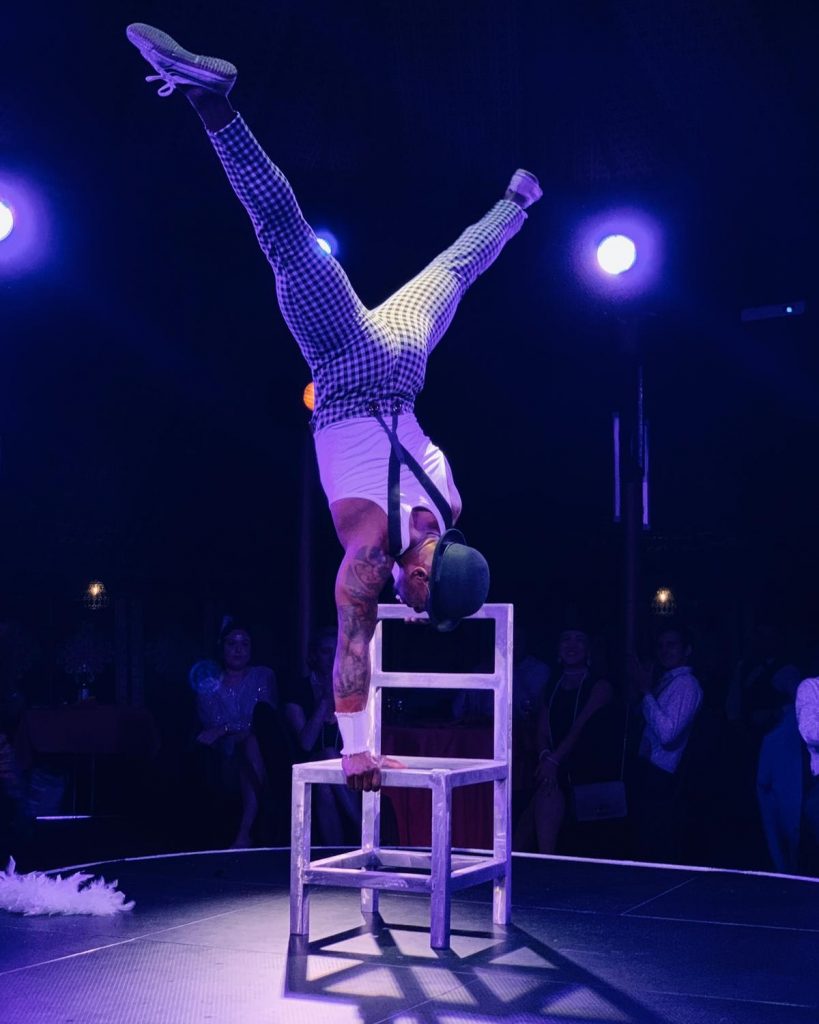 Stuhlakrobatik der Akrobat im Handstand auf Stühlen