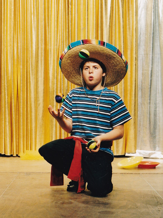 Ein Kind der Zirkus Mitmachshow jongliert mit 3 Bällen und hat einen mexikanischen Hut auf dem Kopf.